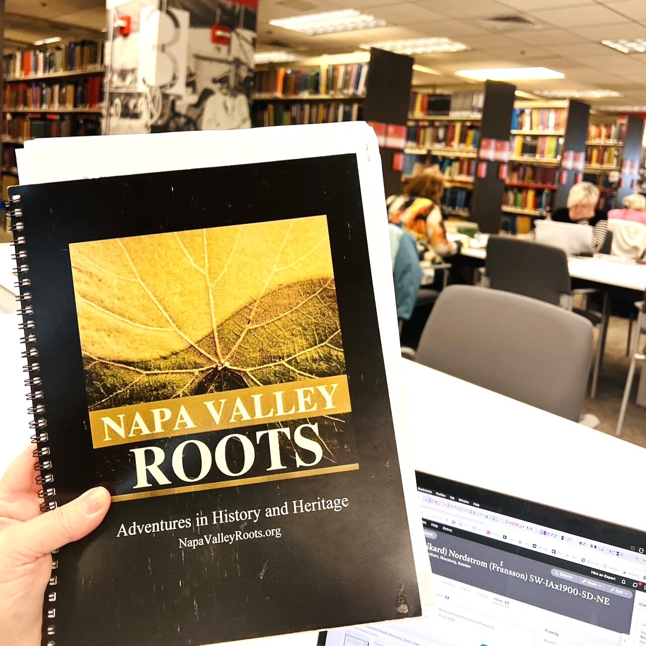 Napa Valley Roots notebook held high against research library backdrop